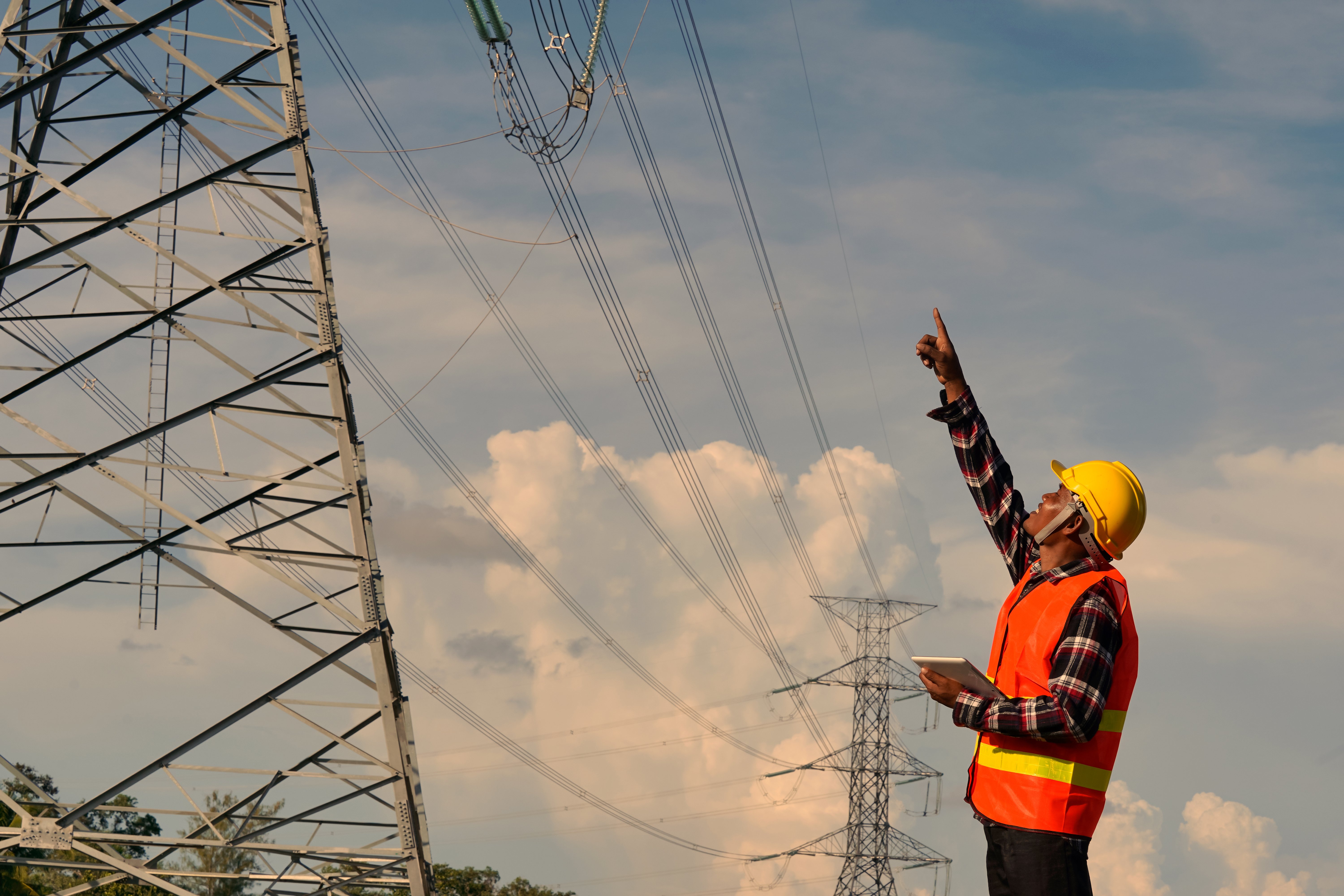 male-engineer-uses-laptop-is-inspecting-construction-work-large-electric-power-pole-front-construction-site